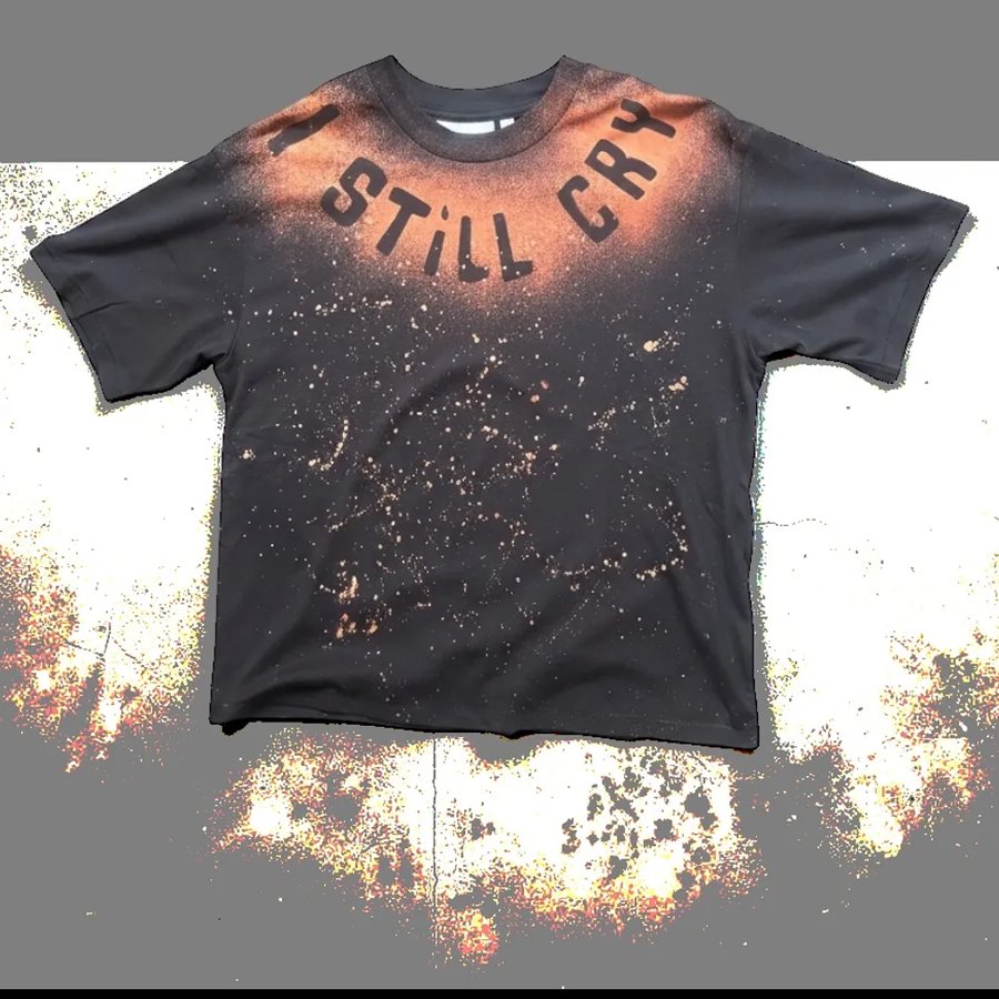 Black oversized tee with rust splatter and "I STILL CRY" lettering around the collar